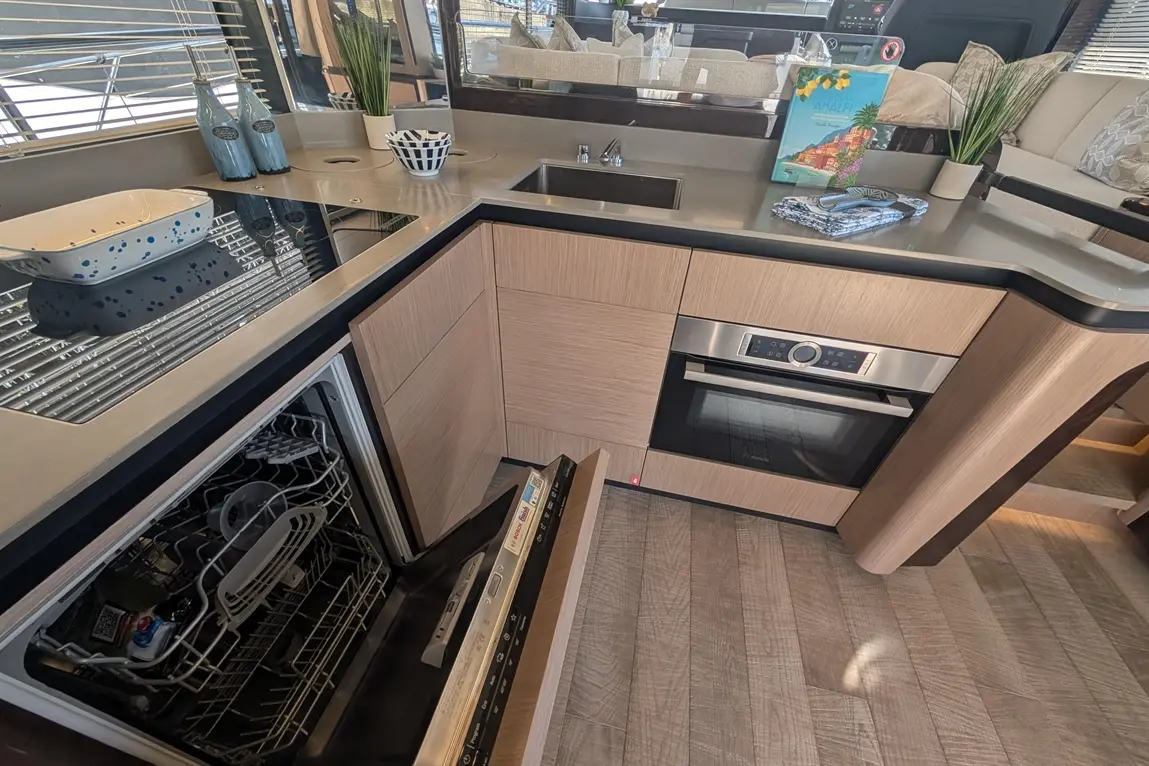 Modern kitchen showcasing an oven, dishwasher, and stylish decor including blue vases and a book on the counter.